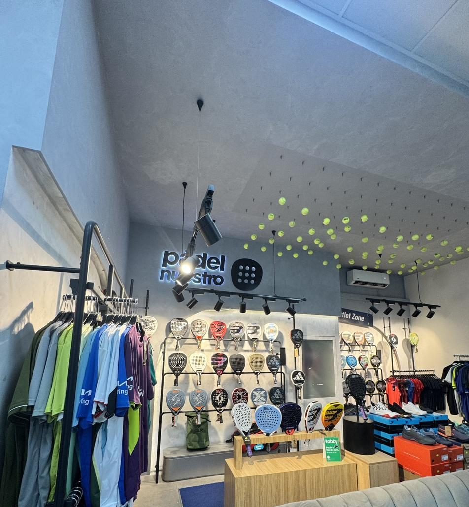 Rackets on the wall under a ceiling of hanging balls